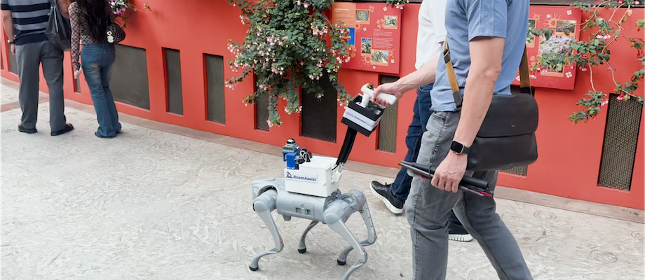A RoamAssist robotic guide dog walking beside a person along a public path at Gardens by the Bay.